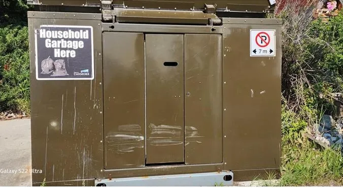 A green organics bin with a metal latching clip, labeled "Wild Safe BC"