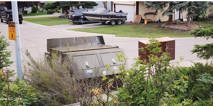 A large metal community garbage bin enclosure in a residential area