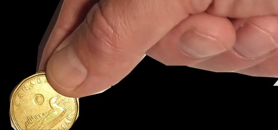 A hand inserting a Canadian loonie coin into a slot at the top of a globe of the Earth.
