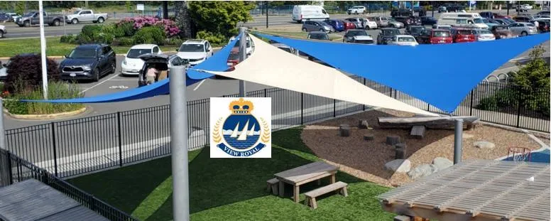Photograph of the Westshore Daycare play area featuring blue and beige shade sails over a playground with picnic tables and woodchip areas.
