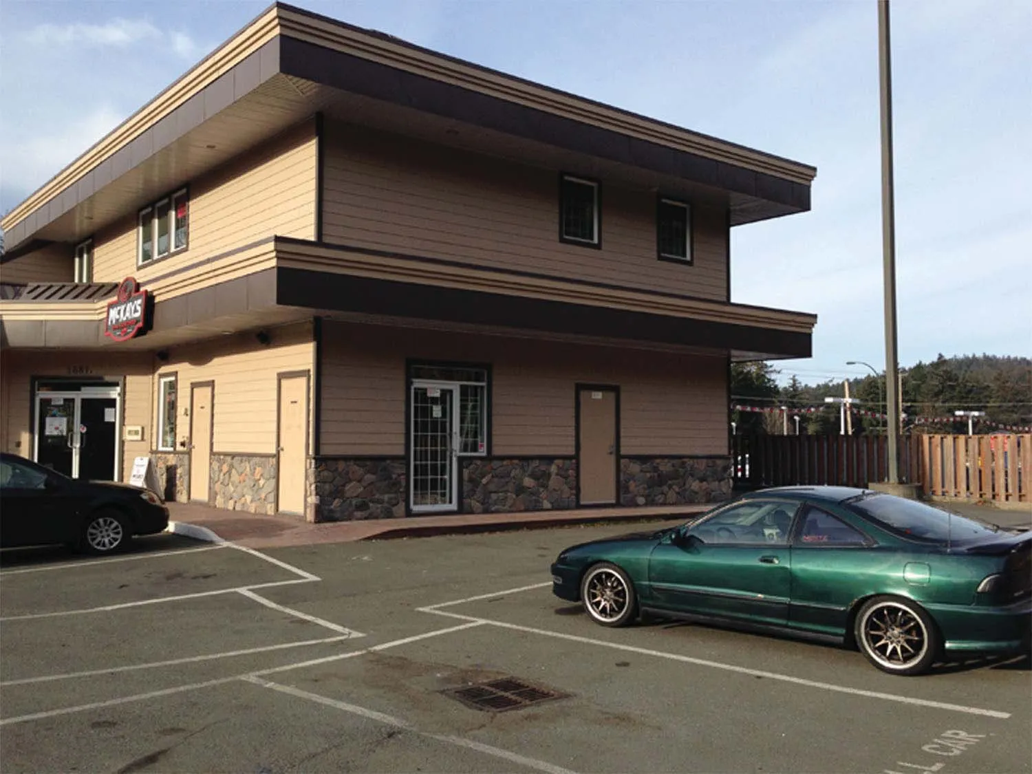 Close-up perspective of the building's exterior with a green car parked in front.