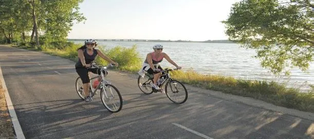 Two people cycling along a paved shoreline path