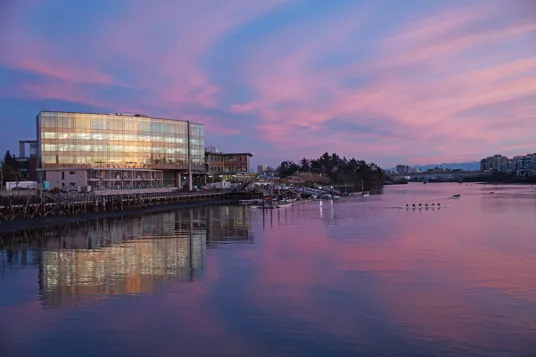 Sunset view of a glass building reflecting in the water at Selkirk Waterfront