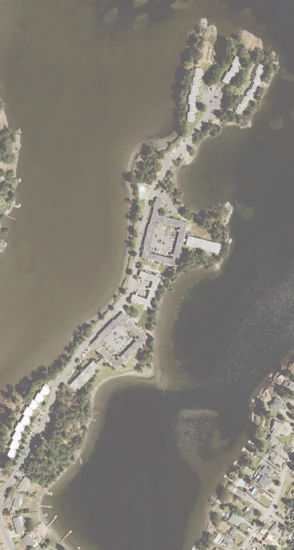 Aerial photograph of the peninsula site showing existing building footprints and surrounding water