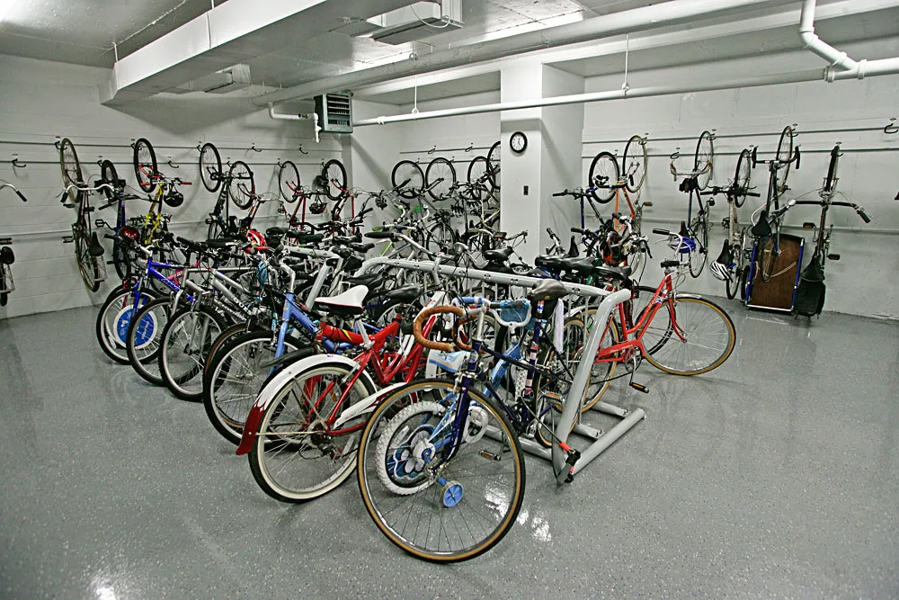 Close-up of bicycles hanging from wall racks in a garage next to parked cars