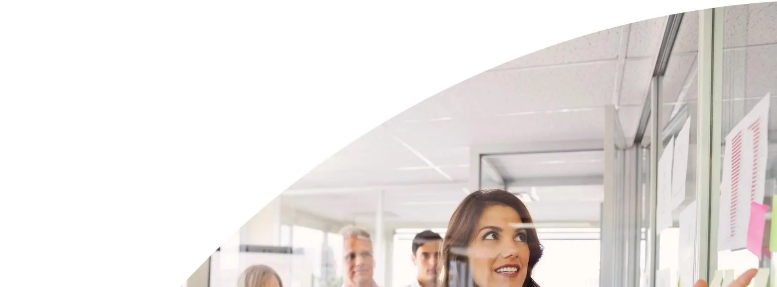 Top portion of a photograph showing office personnel looking at a glass board with notes
