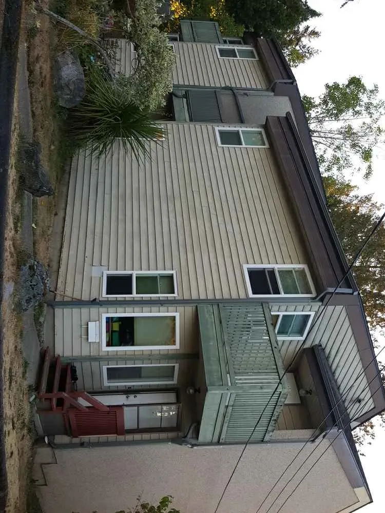 Exterior photo of original building showing lower level with beige siding and a balcony