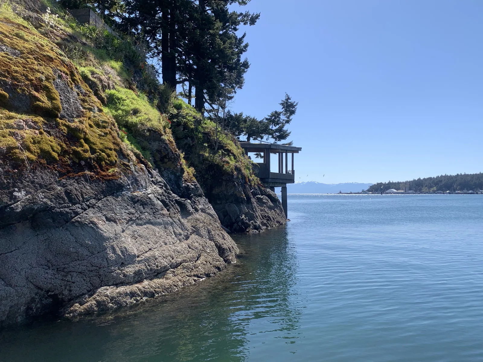 A view from the water of the dock structure built into a rocky, moss-covered cliffside.