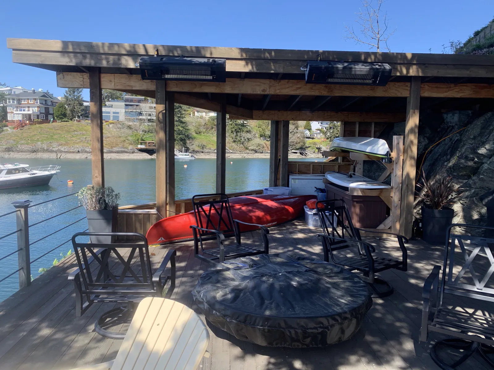 An interior view of the covered deck area featuring seating, a fire pit, and stored recreational equipment.