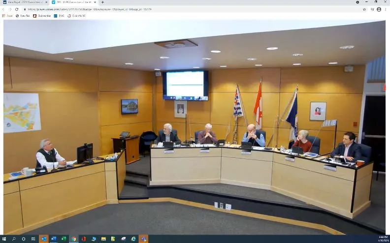Council meeting in progress with various camera angles displayed on screens