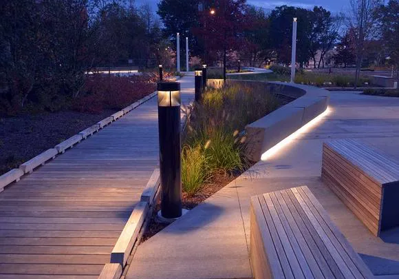 Nighttime photo showing the proposed Selux Inula light bollards and illuminated wooden bench seating.