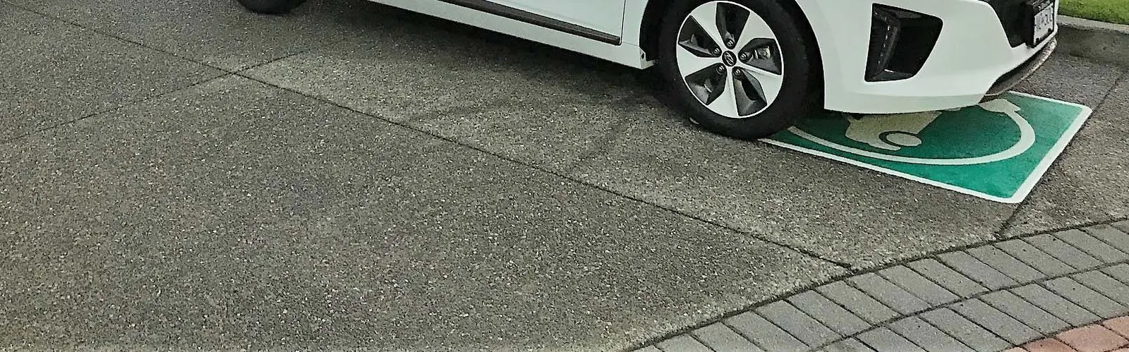 A white View Royal electric vehicle plugged into a charging station outside Town Hall