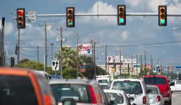 Eye-level photo of traffic signals at an intersection with a queue of cars