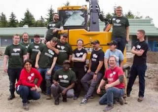 HeroWorks volunteers and donors standing in front of an excavator