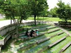 Photo of an open lawn area on a slab with concrete stepwalls for seating and planters