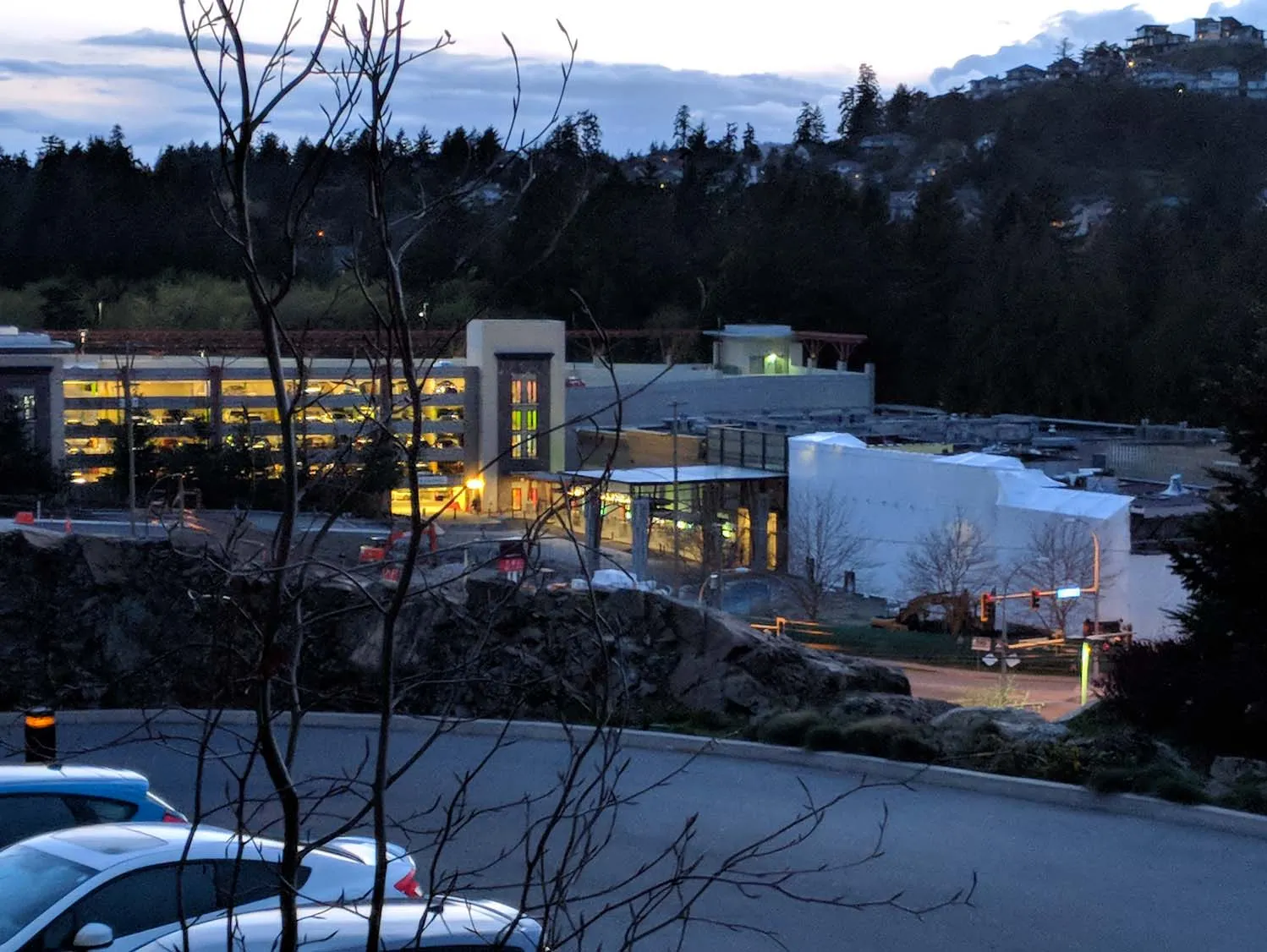 View of the View Royal Casino construction site at dusk from an elevated position, showing the parking garage with lights on and construction equipment
