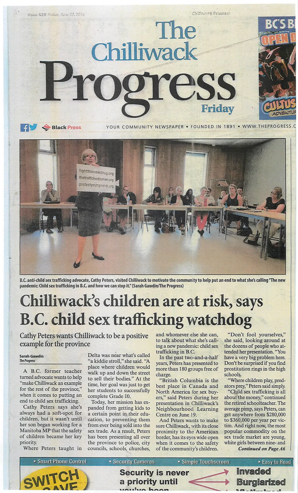 A photograph of Cathy Peters, a B.C. anti-child sex trafficking advocate, standing at the front of a room presenting to a seated audience. She is holding a sign that lists the websites fightthenewdrug.org, thetraffickedhuman.org, and protectyoungminds.org.