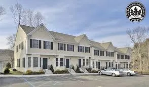 Rendering of a row of light-colored townhouses with a parking area in front