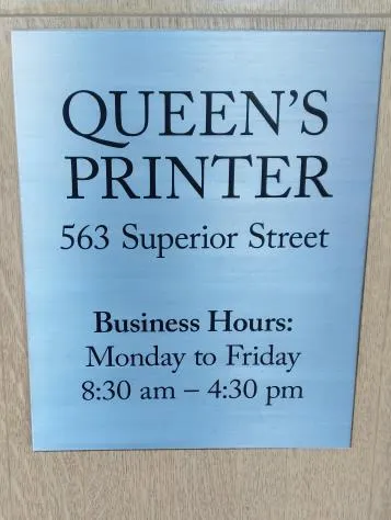 Photo of an example aluminum composite plaque for "QUEEN'S PRINTER" at 563 Superior Street, showing business hours