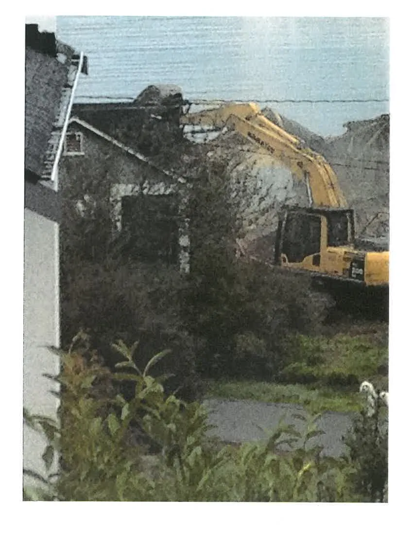 Photo of an excavator at a demolition site of a residential building